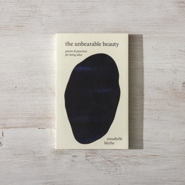 Book titled 'the unbearable beauty' with a black abstract design on a light wooden surface